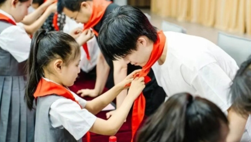 王楚钦弯腰戴红领巾，目光避开小女孩胸膛，结束说谢谢尽显分寸